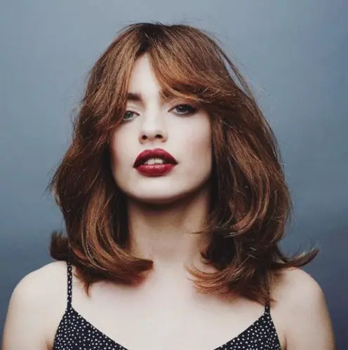 a shaggy layered medium haircut with curtain bangs and a beautiful ginger shade is an amazing solution for the fall