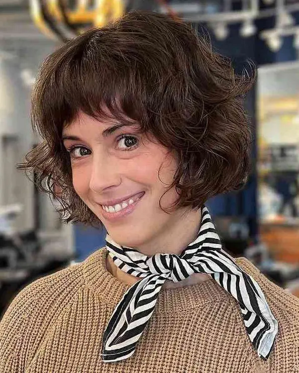 A short stacked French bob with feathered bangs and curls is a lovely and chic idea that is low maintenance