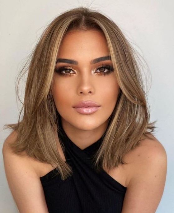 a soft brown outgrown bob with a bit of blonde highlights and soft curtain bangs dyed blonde, too