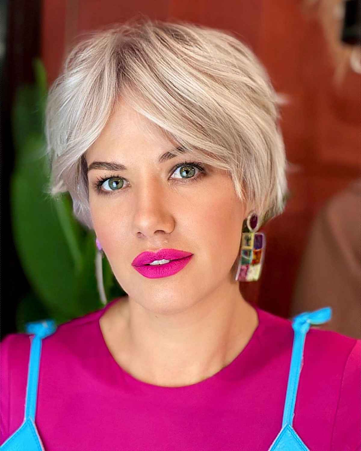 a soft icy blonde pixie haircut with a curtain fringe that complements the face shape