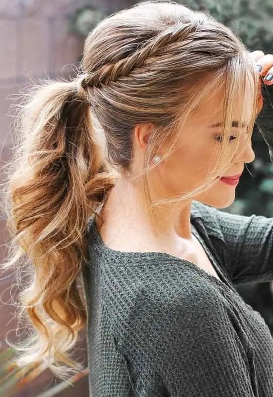 a wavy ponytail with a fishtail braid on one side and some bangs is a relaxed and boho hairstyle idea
