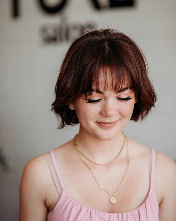 an auburn jaw-ling bob with wispy bangs makes a statement with color and accent the face the best way possible