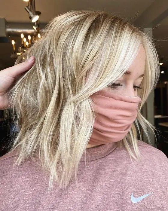 beautiful blonde hair with icy blonde balayage, with waves and curtain bangs looks very chic and very stylish