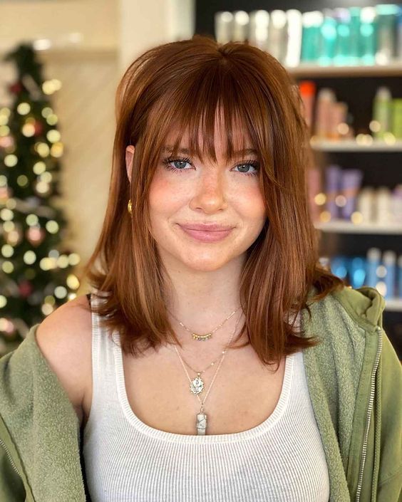 dark ginger medium-length hair with wispy bangs looks lovely and effortless and you can make a statement with color