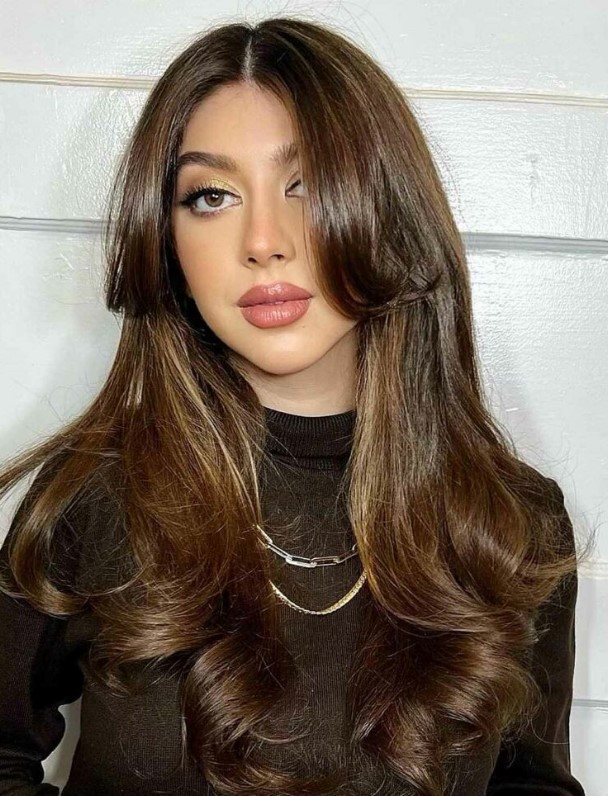 Fab long dark brown hair and central parting, curls, long face framing layers and curtains bangs that are low maintenance
