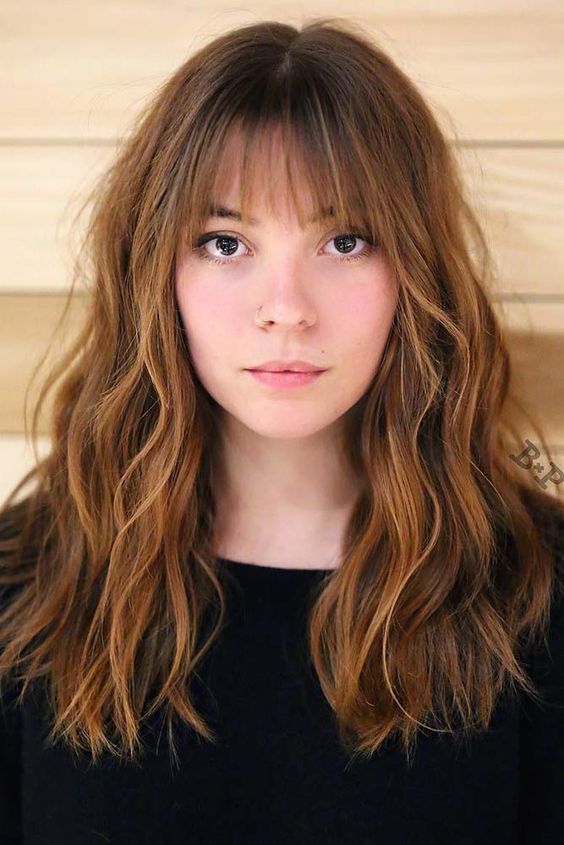 gorgeous long cinnamon-colored hair with caramel and golden blonde balayage, waves and wispy bangs