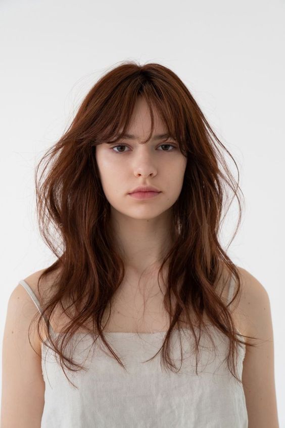 Long and wavy layered cinnamon colored hair with wispy bangs is a super cool idea to make a statement with color