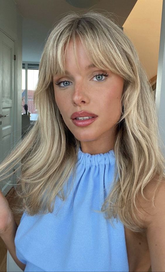long blonde hair with waves and layered bangs, with curtain and wispy ones, is a lovely idea
