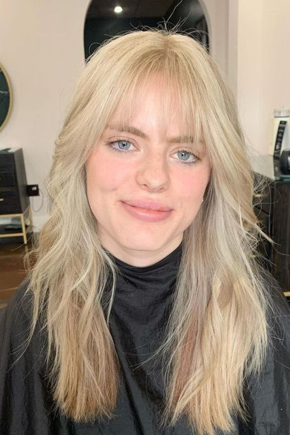 long blonde hair with waves and wispy bangs is a cool and chic idea to rock, it looks effortless