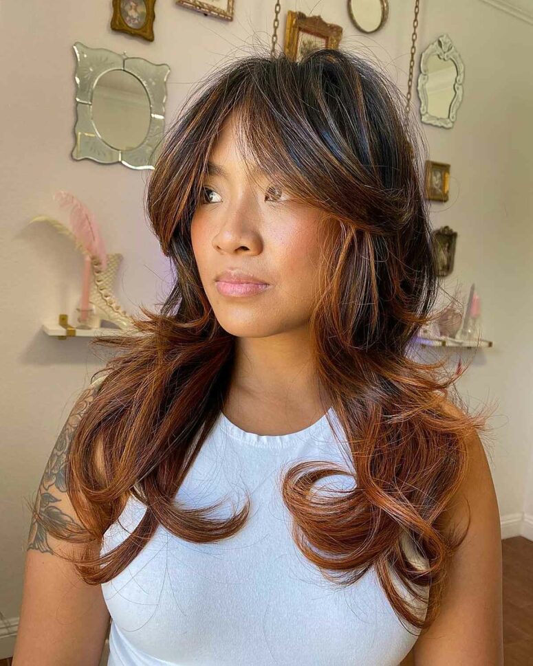 long dark hair with caramel balayage, curls and soft curtain bangs is a very stylish and chic idea to remove weight from thick hair