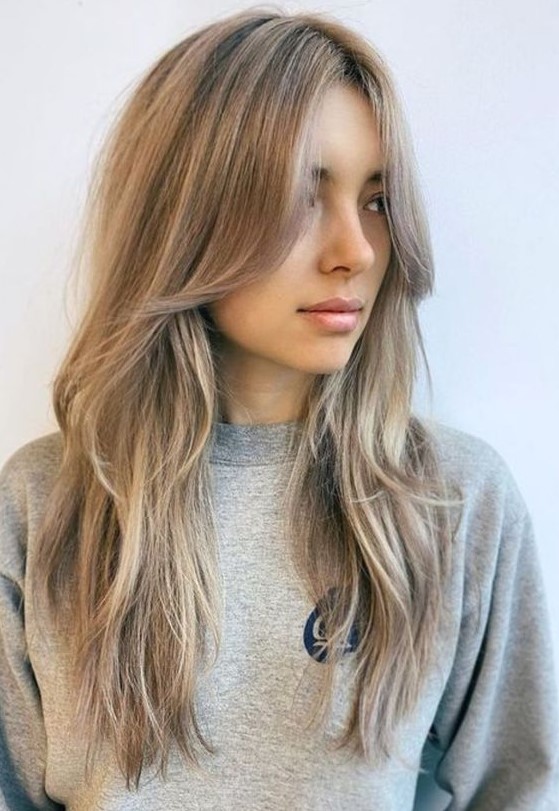 long mushroom blonde hair with a slight balayage and long curtain bangs that perfectly frame the face