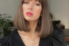 medium length brunette hair with wispy bangs and rounded ends looks doll-like and chic