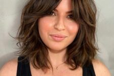 a beautiful dark brunette long bob with waves and bottleneck bangs features dimension and is ultimately cute