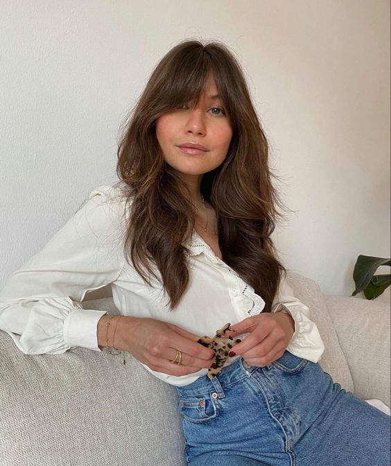 a beautiful long brunette wolf cut with camaral balayage and bottleneck bangs looks very 70s inspired and cool