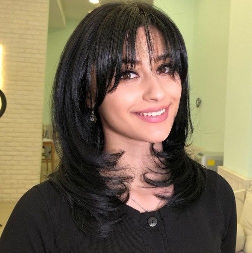 a black medium butterfly haircut with wispy to curtain bangs and curled ends is a lovely idea if you have shoulder-length hair