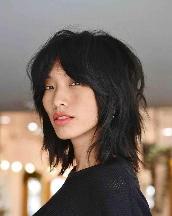 a black wolf cut with bottleneck bangs and layers, with central part is a catchy idea, and styled with messy waves it looks edgier