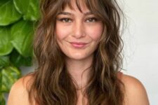 a brown long wolf haircut with wispy bangs, caramel balayage and soft waves to make the cut look cuter