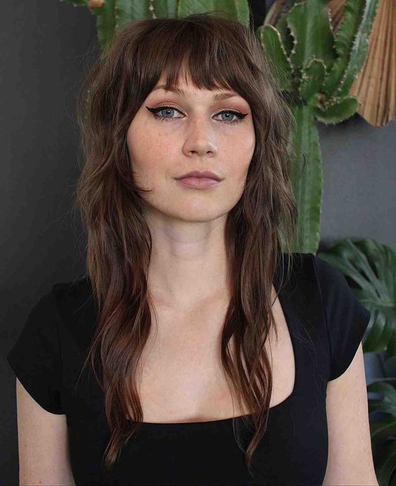 a brunette wolf cut with bangs and waves down looks pretty and very stylized and will give you a 70s look