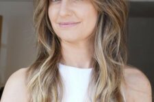 a brunette wolf cut with bottleneck bangs and waves down plus blonde balayage is a super chic idea