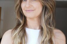 a brunette wolf cut with bottleneck bangs and waves down plus blonde balayage is a super chic idea