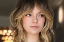 a chic medium wolf cut with waves, blonde balayage and bottleneck bangs is a catchy idea