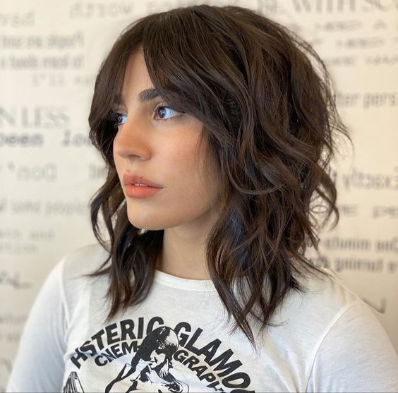 a cool brown medium wolf cut with waves that make it softer and bottleneck bangs is a lovely idea
