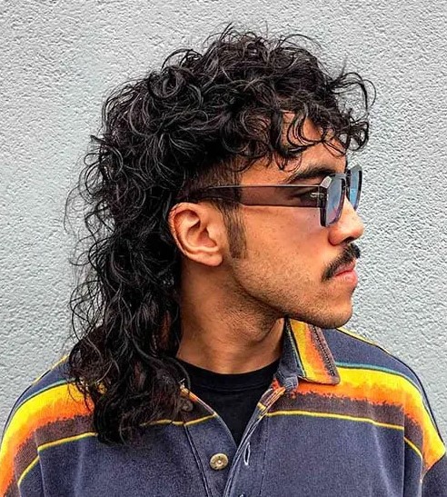 a curly hair wolf cut resembles a mullet and emphasizes the long and flowing curls in the back