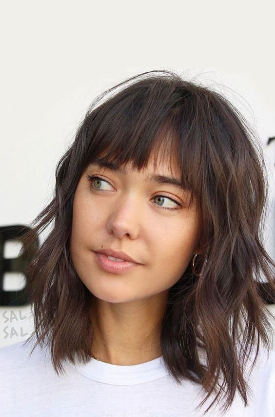 a cute shaggy dark brunette long bob with bottleneck bangs and waves is a cool and bold idea