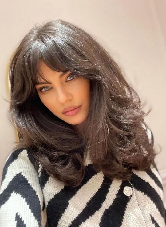 a dark brunette medium butterfly haircut on thick hair, with bottlneck bangs and waves is wow