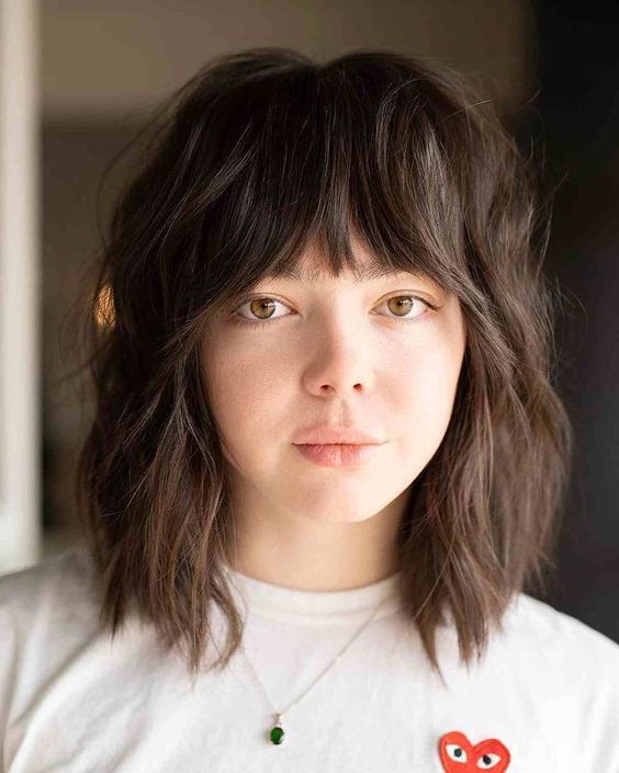 a dark brunette medium wolf cut with blunt bangs and messy waves is a very up-to-date idea