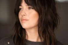 a dark brunette medium wolf cut with bottleneck bangs and messy waves is a cool and trendy idea for now
