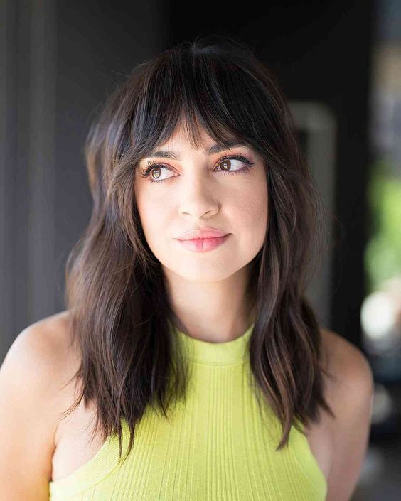 a dark brunette wavy hairstyle with bottleneck bangs is a trendy and up-to-date idea to rock