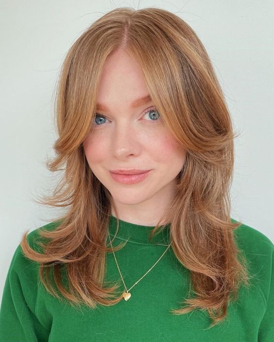 a ginger medium butterfly haircut with long curtain bangs and curled ends is a lovely solution