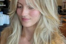 a gorgeous long blonde wolf haircut with curtain bottleneck bangs, messy waves down is a lovely hairstyle with much volume