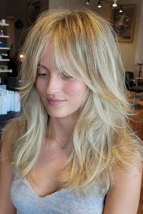 a gorgeous long blonde wolf haircut with curtain bottleneck bangs, messy waves down is a lovely hairstyle with much volume
