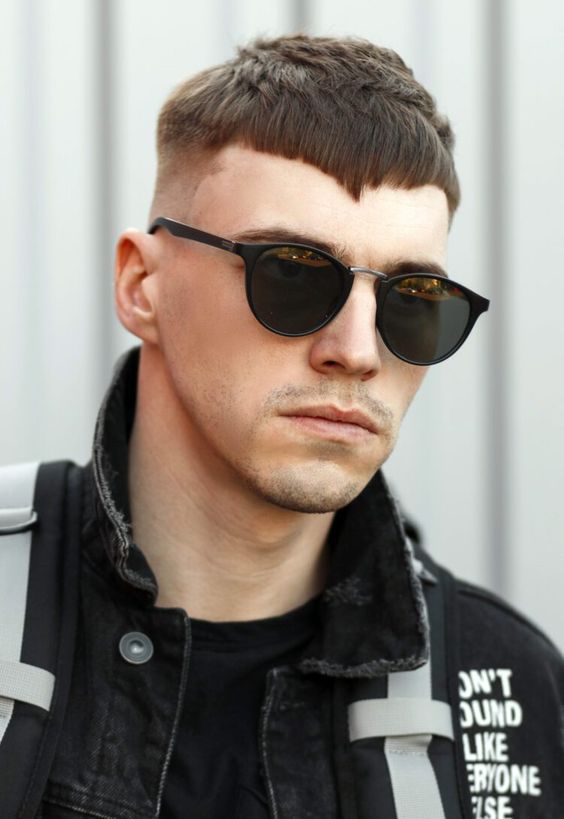 a high fade haircut with thick longer hair on top and an angular fringe looks really bold and cool