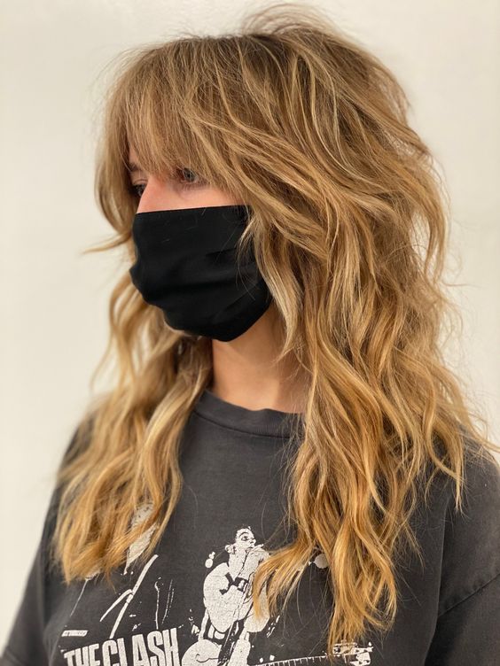 a honey blonde wolf cut with bottleneck bangs and waves down plus messy texture is a very chic idea