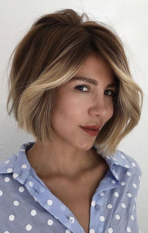 A jaw length dark brunette bob with a blonde money piece and a lot of volume looks very chic and cool