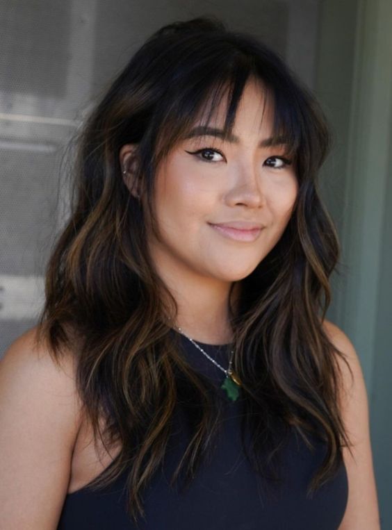 a long black wolf haircut with caramel balayage, wispy bangs and waves is a lovely and cool idea