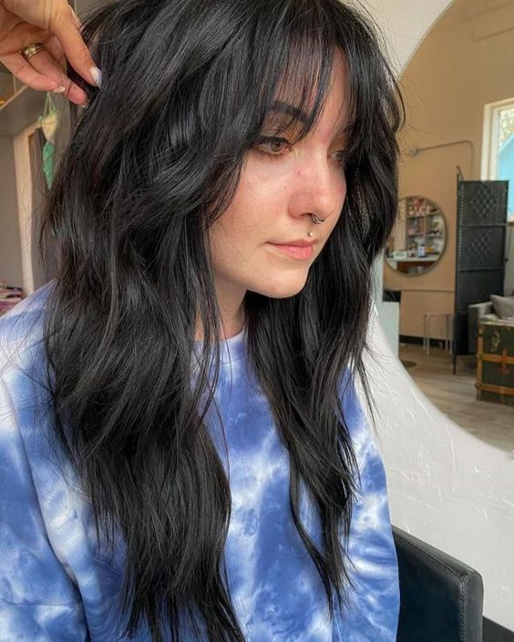a long black wolf haircut with wispy bangs and messy waves is a cool and catchy idea for a modern look