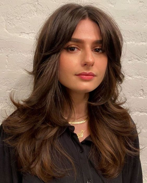 a long brown butterfly haircut with curled ends and short curtain bangs is a chic and lovely idea
