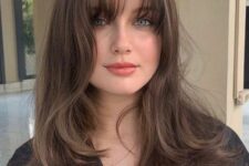 a long brunette wolf cut with bottleneck and wispy bangs and waves looks luxurious and very eye-catching