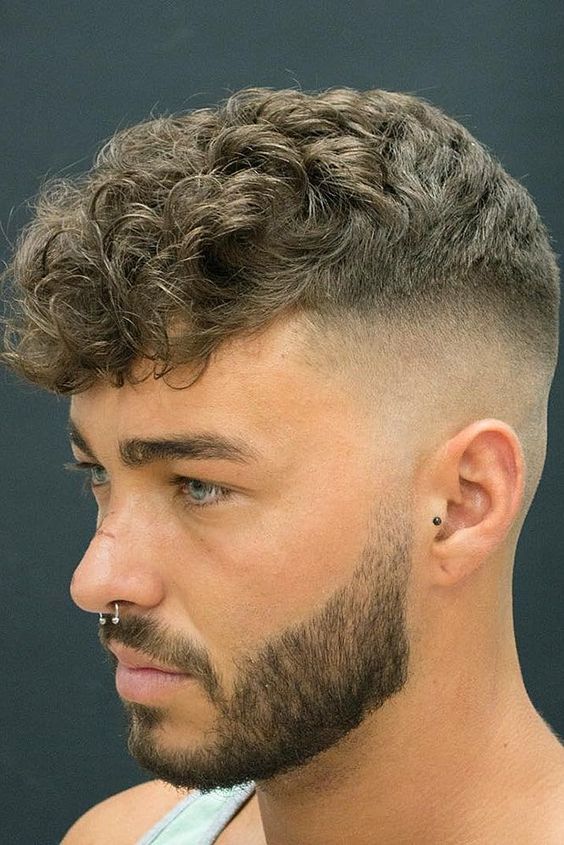 a longer curly tpo paired with a high undercut fade and a stylish beard is a lovely idea for a modern guy