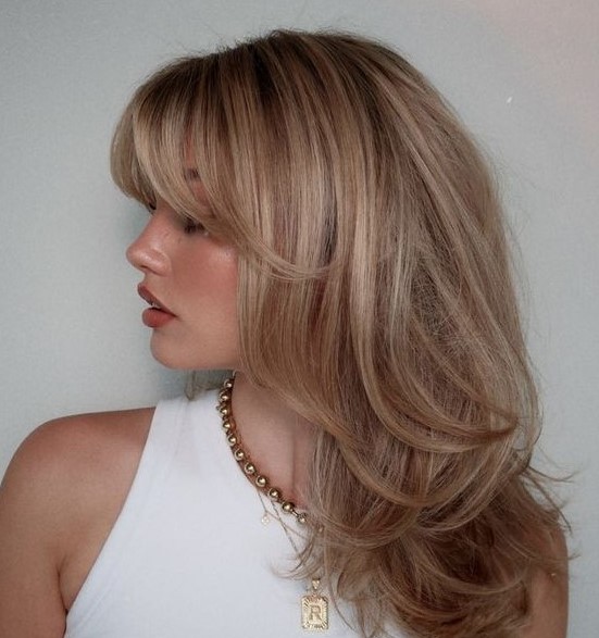 a lovely blonde butterfly haircut with highlights and side and bottleneck bangs is a gorgeous idea