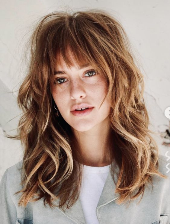 a medium ginger wolf cut with blonde balayage and wispy bangs plus waves is a chic and catchy idea
