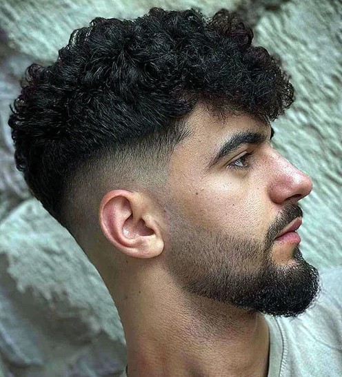 a mid fade curly haircut is a stylish and balanced idea, the fade contrasts the longer curls on top