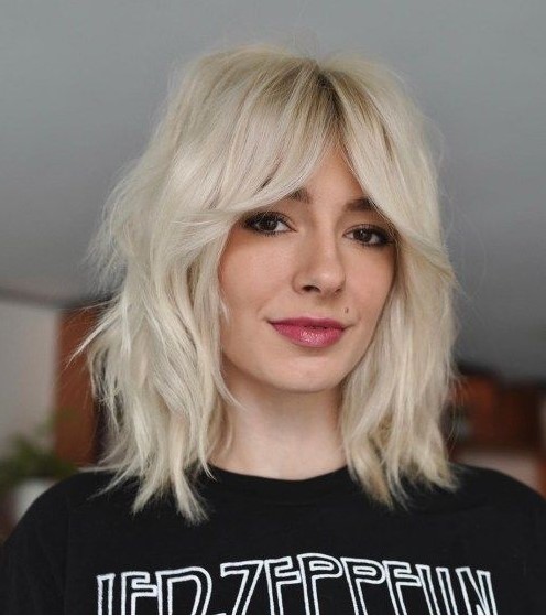 a platinum blonde medium wolf cut with bottleneck bangs and messy texture is a chic and bold solution