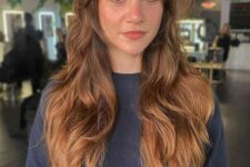 a pretty ginger brunette wolf cut with curtain bangs, waves and volume is a super cool and chic idea