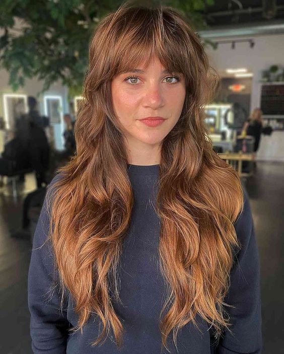 a pretty ginger brunette wolf cut with curtain bangs, waves and volume is a super cool and chic idea