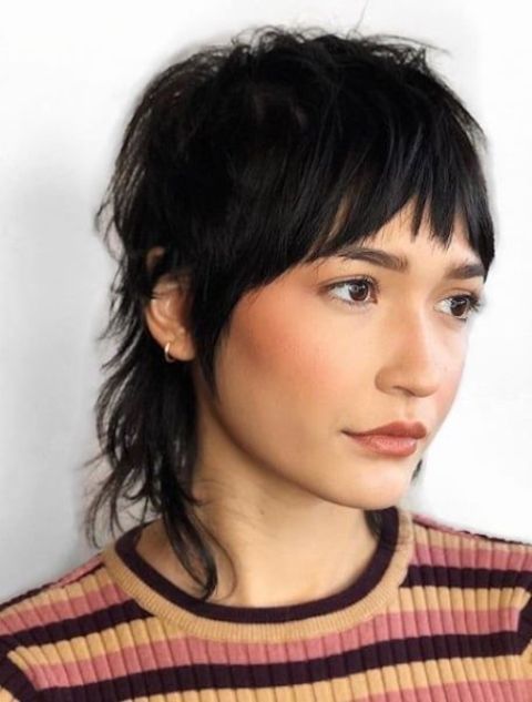 a short black mullet with bangs and shaggy touches is a cool idea that feels and looks very retro-like